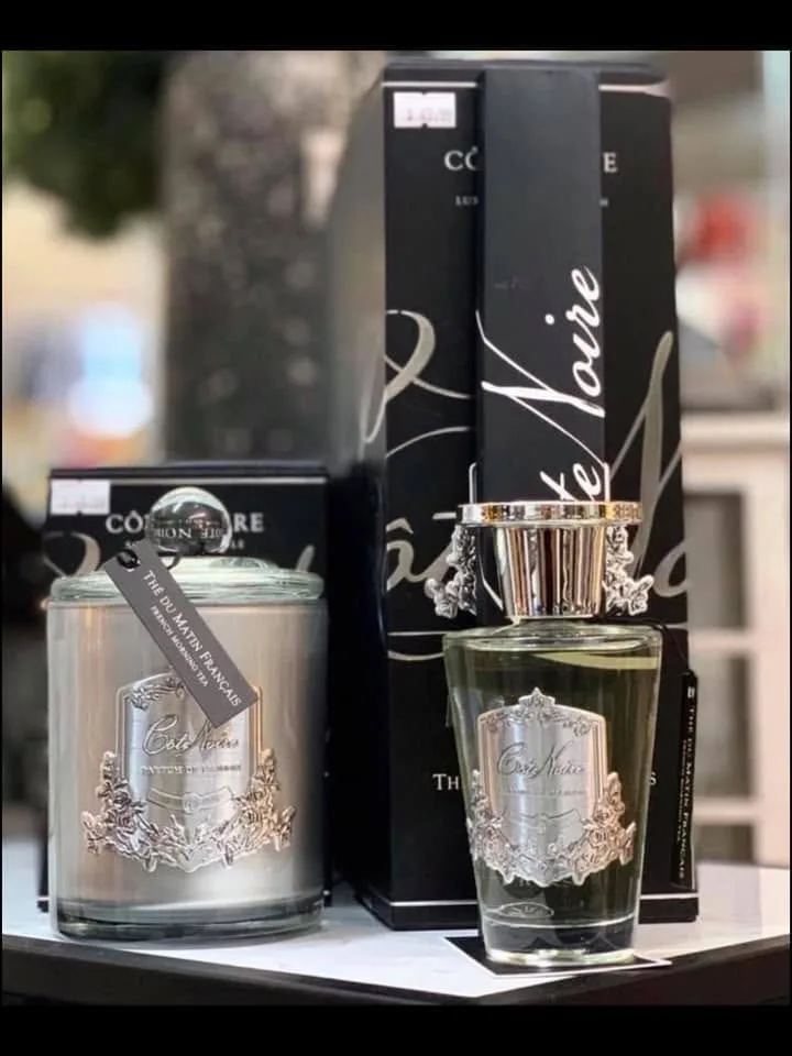 Côte Noire silver candle and tall diffuser bottle with black 'Thé du Matin Français' tagged boxes on a shelf by the window