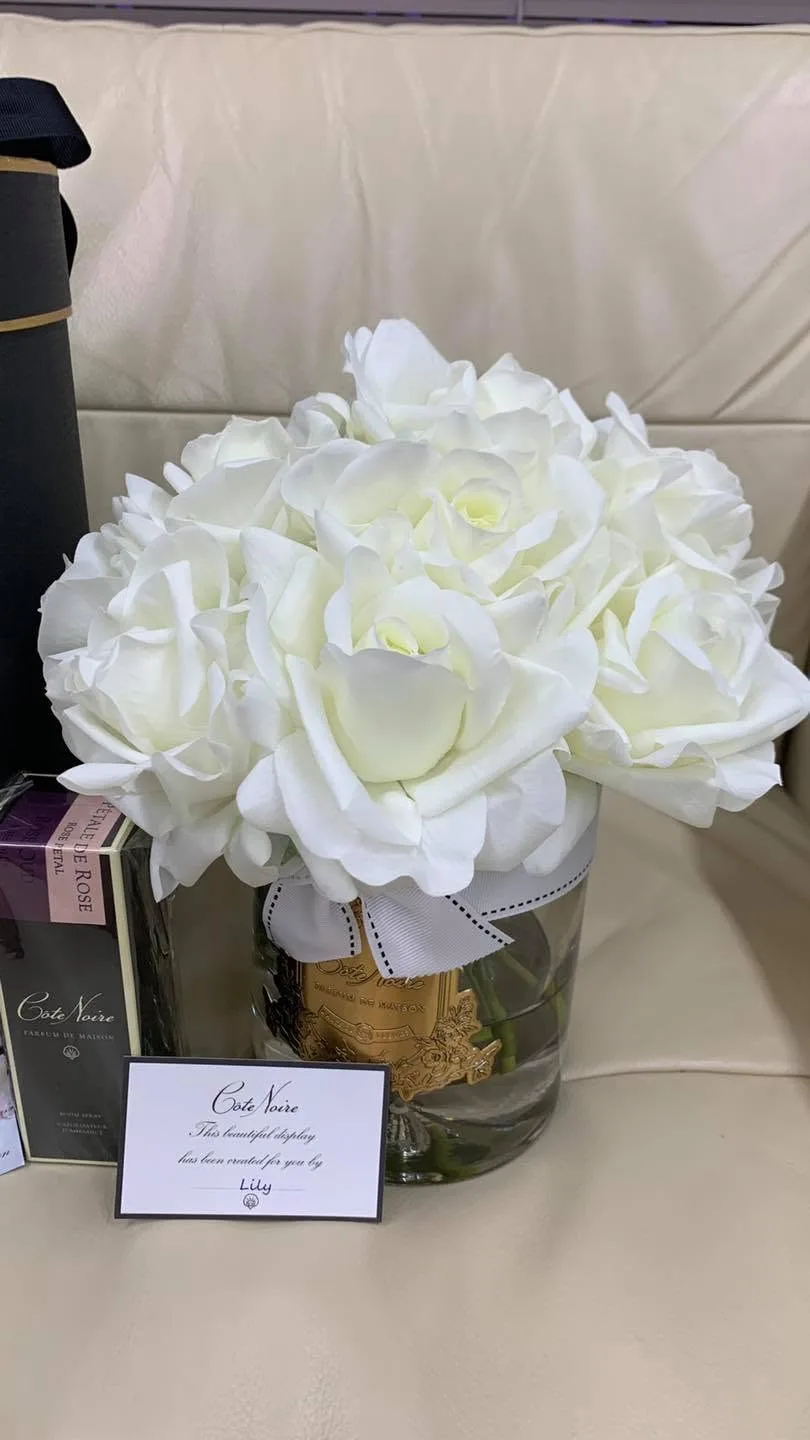 Côte Noire white perfumed roses in a glass vase with 'created for you by Lily' card, Rose Petal box, on a cream sofa