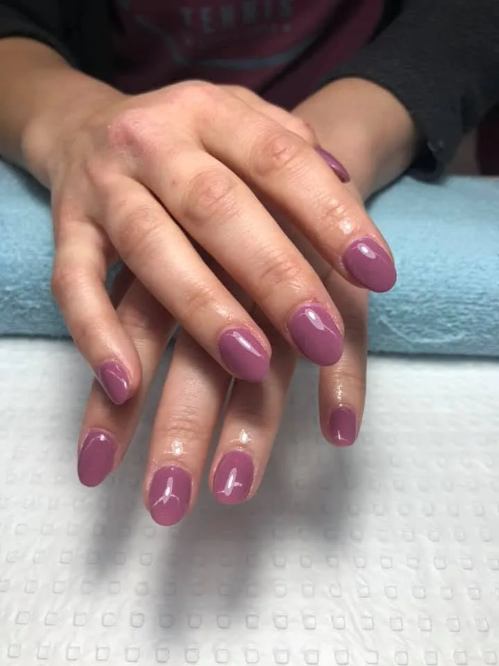 Mauve and rosewood short round gel nails on a blue towel with a white textured mat