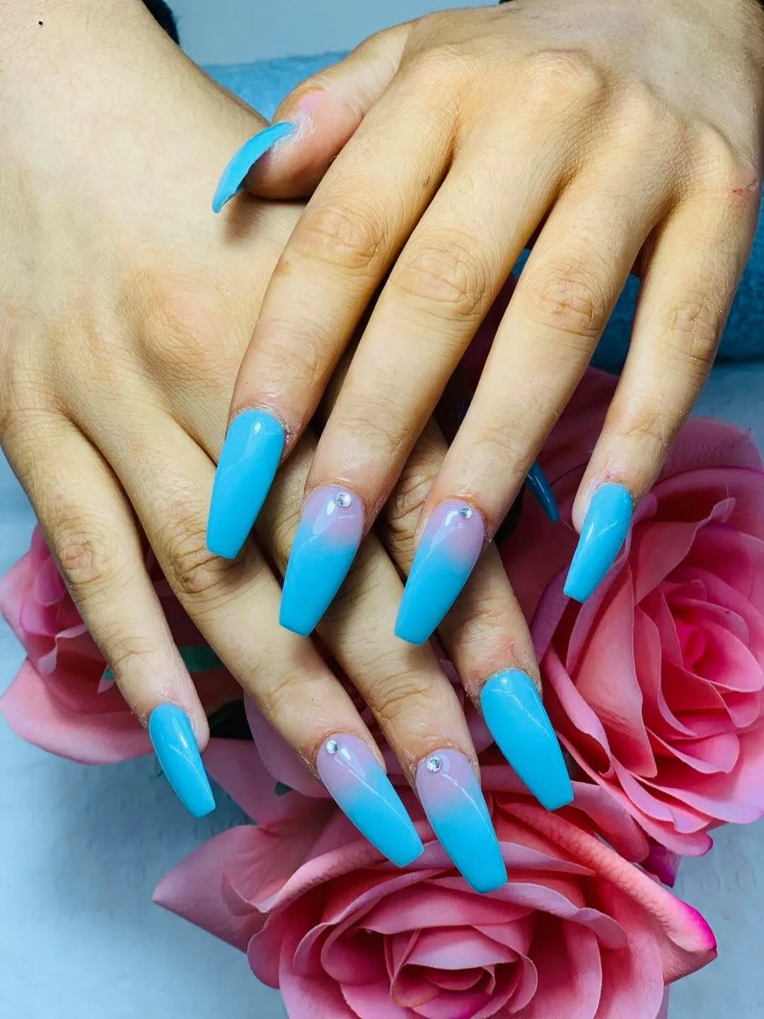 Long baby-blue coffin nails with ombre finish and rhinestones